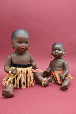 pair of african dolls sitting next to each other on a pink background