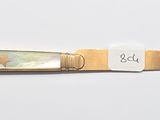 un petit couteau muni d'une étiquette, posé sur une surface blanche