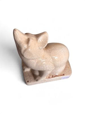 une petite figurine représentant un chat posée sur une surface blanche