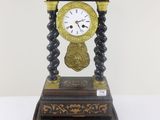 une horloge noire et dorée posée sur une table blanche