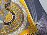 a yellow and black scarf with a gold medallion on it