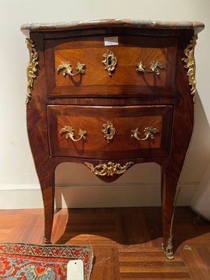 a small wooden chest of drawers on display in a room