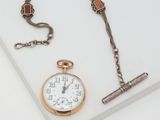 a pocket watch and a chain on a white surface