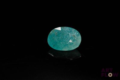 a close up of a green gemstone on a black surface