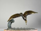 sculpture en bronze représentant un oiseau volant au-dessus d'une vague, posée sur un socle en marbre