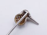 a silver and gold pin with a spoon in it