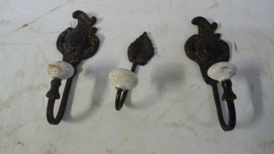 trois crochets muraux anciens en fonte sur un fond blanc