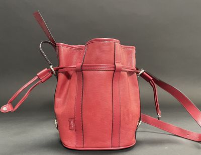 red leather handbag with strap on grey background
