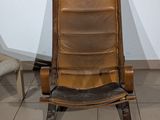 a brown leather chair sitting next to a chair on a tiled floor