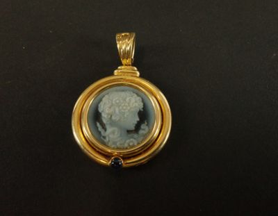 un gros plan d'un pendentif plaqué or orné d'un camée représentant une femme