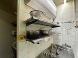 a kitchen with a sink, stove, and shelves with pots and pans on them