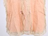 peach colored blouse hanging on a hanger on a white wall