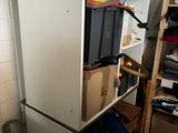 a white refrigerator in a small room with boxes on top of it