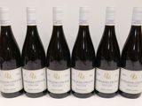 six bouteilles de vin sont alignées sur une table