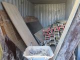 un tas de bois dans un conteneur où se trouve une brouette