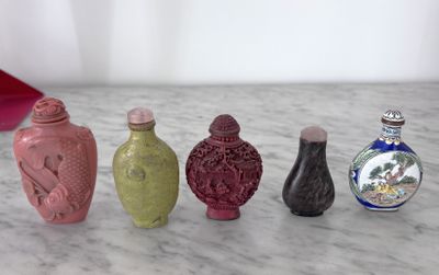 cinq vases de couleurs différentes posés sur un plan de travail en marbre
