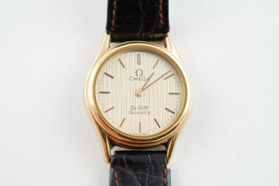 a gold wrist watch with a black leather strap