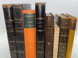 several old books are lined up in a row on a white surface