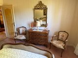 a bedroom with a bed, dresser, chair and mirror in it