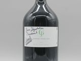une bouteille contenant un liquide noir posée sur une table blanche
