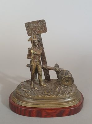 figurine en bronze représentant un homme tenant une pancarte et accompagné d'un chien