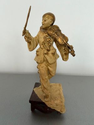 gold figurine of a man holding a sword on a wooden base