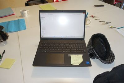 a laptop computer sitting on a table with a hat on top of it