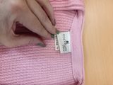 a person that is putting a label on a pink sweater