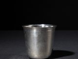 a silver cup sitting on a black surface with a black background