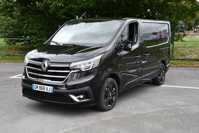 La camionnette noire est garée sur le parking, près des arbres.