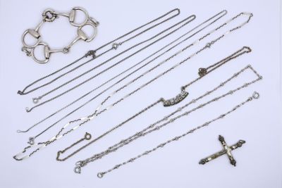 various silver necklaces and bracelets laid out on a white surface