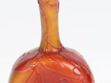un vase rouge et jaune posé sur une surface blanche