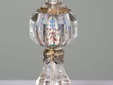 a glass bottle with a gold decoration on top of it
