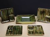 quatre assiettes et plateaux verts et blancs posés sur une table