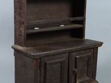 une vieille armoire en bois à deux portes, surmontée d'une étagère