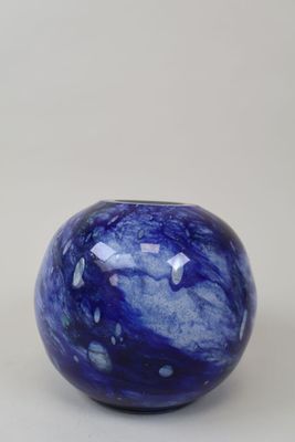 un gros plan d'une boule de verre bleue posée sur une surface blanche