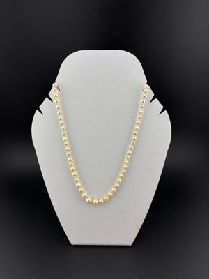 a pearl necklace on a mannequin display with a black background