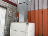 a white refrigerator sitting outside of a building next to a green trash can