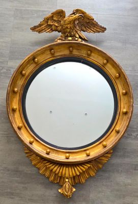 un miroir doré orné d'un aigle, accroché au mur