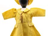 poupée portant un manteau jaune et un chapeau à col blanc