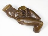 sculpture en bronze représentant un bébé tenant un biberon, posée sur une surface blanche