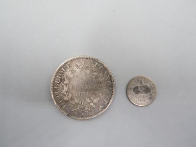 une vieille pièce d'argent et une petite pièce d'argent posées sur une surface blanche