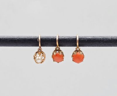 une paire de boucles d'oreilles en or ornées de pierres orange, montées sur un fil métallique