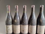 six bottles of red wine are lined up on a table