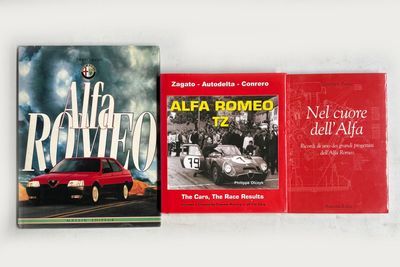 deux livres posés sur une surface blanche, avec une voiture rouge en arrière-plan