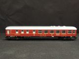 the red and white train car is sitting on the black surface