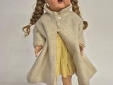 a small doll that is wearing a coat and shoes