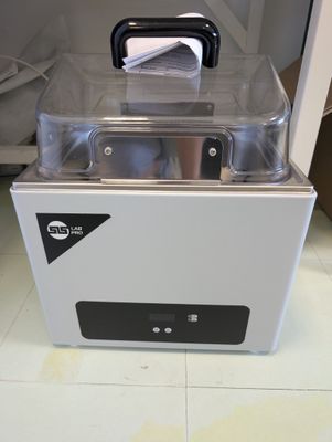 une boîte blanche munie d'un couvercle transparent, posée sur un sol carrelé