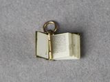 a small open book with a key hanging from it