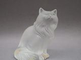 une figurine de chat blanc posée sur une surface grise